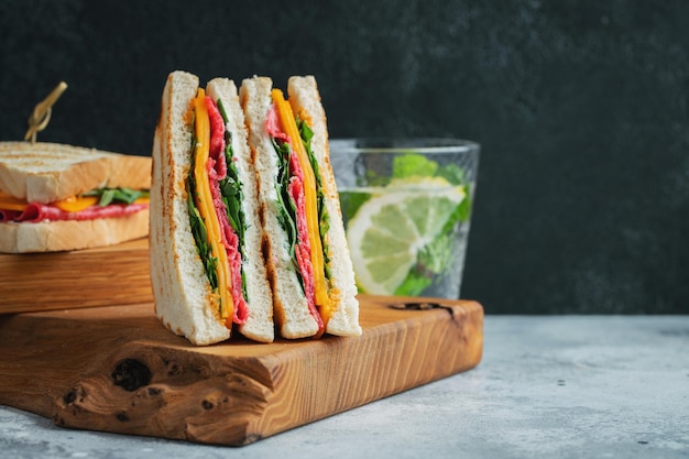 Due panini fatti in casa con formaggio salsiccia e arugula su uno sfondo di cemento chiaro