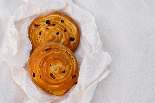 Due panini freschi con uvetta e crema di banana, su carta da forno, su sfondo chiaro