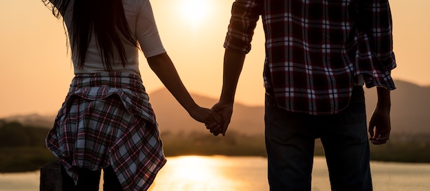 Due partner che si tengono per mano davanti alla montagna durante il tramonto