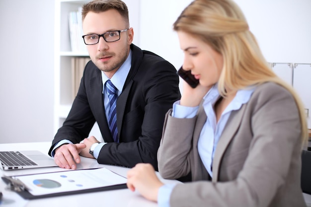 Due partner commerciali di successo che lavorano alla riunione in ufficio. Concentrati sulla bionda mentre parli al telefono.