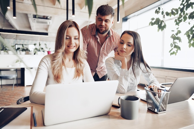 Due partner commerciali femminili e uno maschile che guardano lo schermo del computer e discutono del loro progetto