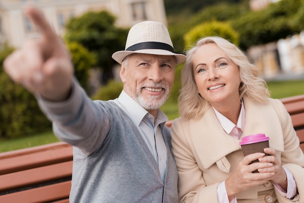 Due pensionati sono seduti su una panchina con un bicchiere di caffè