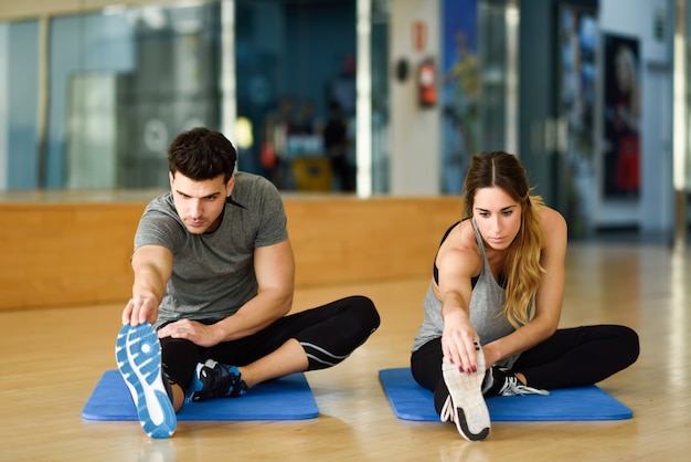 Due persone che allungano le gambe in palestra.