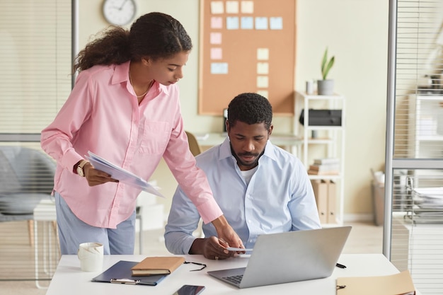 Due persone che lavorano in ufficio con una direttrice che istruisce un collega