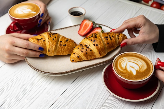 Due persone che mangiano un croissant e una tazza di caffè.