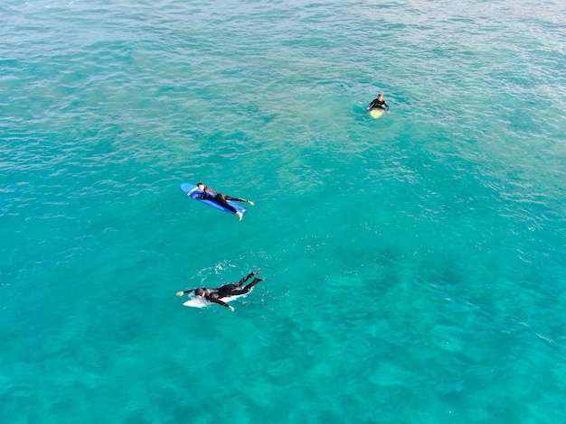 Due persone che remano nell'acqua con le parole scuola di surf sul fondo.