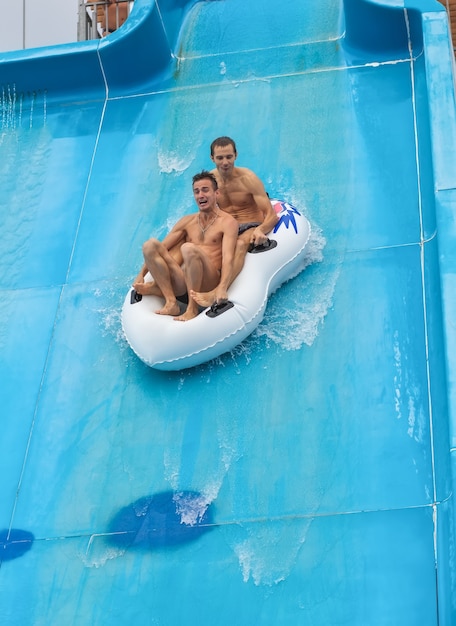 Due persone in uno scivolo d'acqua in spiaggia