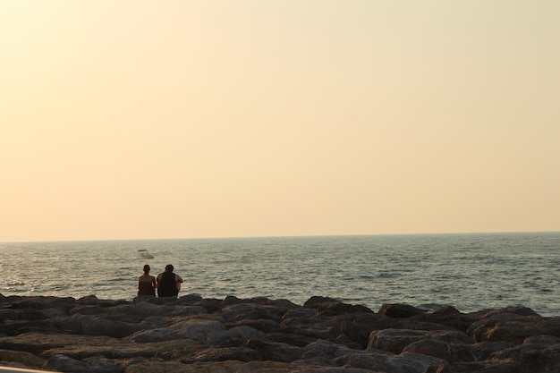 due persone sono in piedi su rocce vicino all'oceano