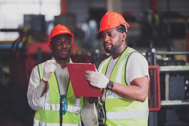 Due persone uomo nero afroamericano lavoratore controllo macchina pesante in fabbrica