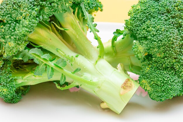 Due pezzi di broccoli freschi e crudi su cavolo verde crudo piatto bianco