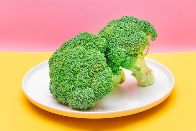 Due pezzi di broccoli freschi e crudi su cavolo verde crudo piatto bianco