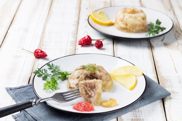 Due piatti di carne fredda e pollo con fette di limone, senape e adjika.