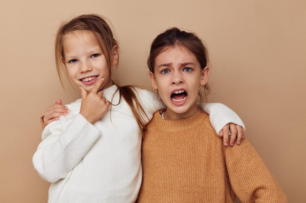 Due piccole amiche divertenti che abbracciano insieme fondo isolato