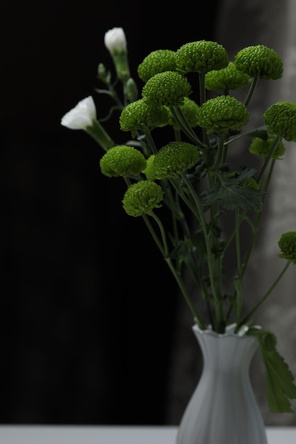 Due piccole rose bianche adornano un bouquet di crisantemi verdi