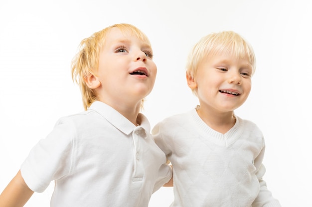 Due piccoli fratelli caucasici con sorrisi biondi e biondi capelli rossi, ritratto isolato sul muro bianco