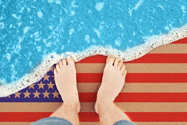 Due piedi sulla soleggiata spiaggia di sabbia con bandiera USA Vista dall'alto sul surf