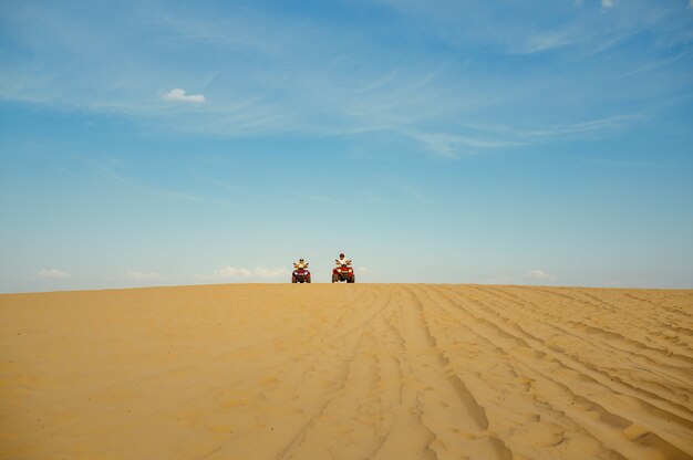 Due piloti in sella a un atv nel deserto, vista da lontano