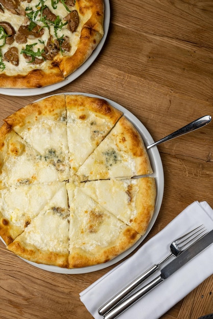 Due pizze su un tavolo di legno con forchetta e coltello