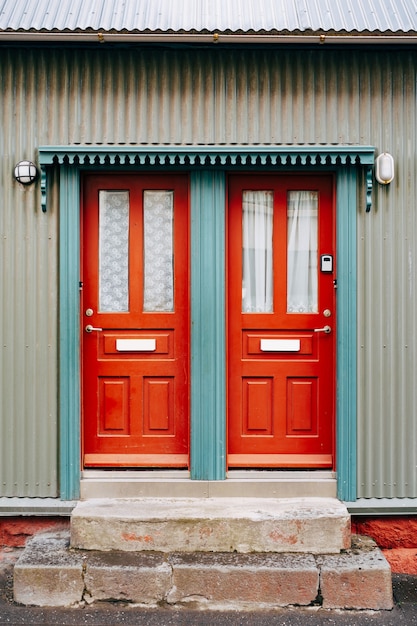 Due porte d'ingresso arancioni con vetro e tende in una porta blu
