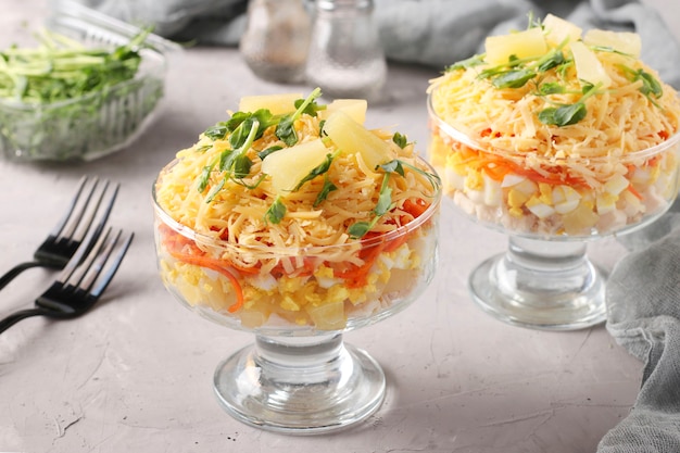 Due porzioni di insalata di pasta sfoglia con pollo, formaggio, ananas, uova e carote