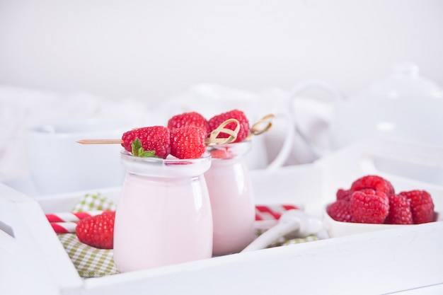 Due porzioni di yogurt naturale fatto in casa in un barattolo di vetro con lampone fresco. Concetto di colazione.