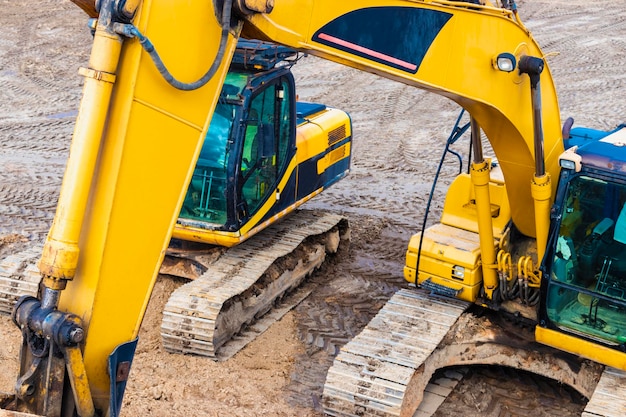 Due potenti escavatori lavorano contemporaneamente in un cantiere edile soleggiato cielo blu sullo sfondo Macchine edili per lavori di sterro