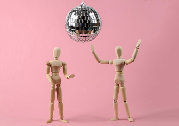 Due pupazzi che ballano sotto la palla da discoteca su sfondo rosa Concetto di festa minimalista