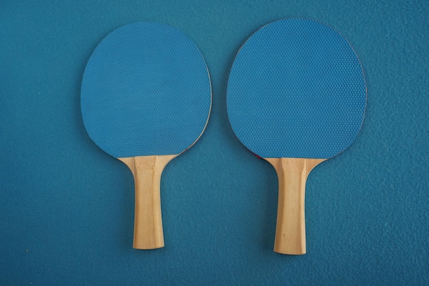 Due racchette blu da ping pong o da ping pong giacciono su uno sfondo blu con una vista in primo piano dall'alto Gioco per il tempo libero Attrezzatura sportiva Competizione internazionale Ping pong Stile di vita sano