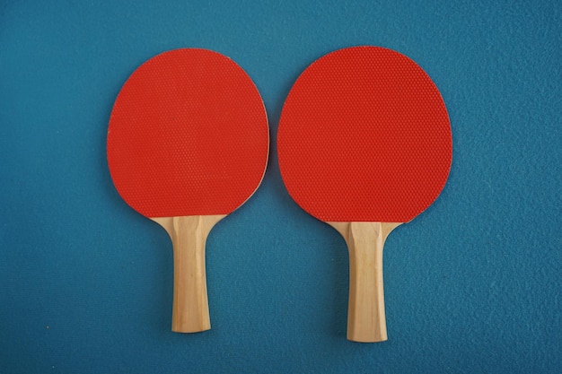 Due racchette rosse da ping pong o da ping pong giacciono su uno sfondo blu con una vista in primo piano dall'alto Gioco per il tempo libero Attrezzatura sportiva Competizione internazionale Ping pong Stile di vita sano
