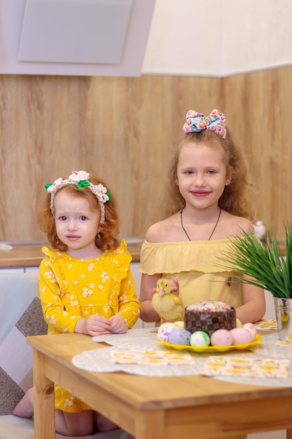 Due ragazze a Pasqua con piccoli anatroccoli gialli Accanto alla torta e alle uova dipinte Holiday Family Happiness