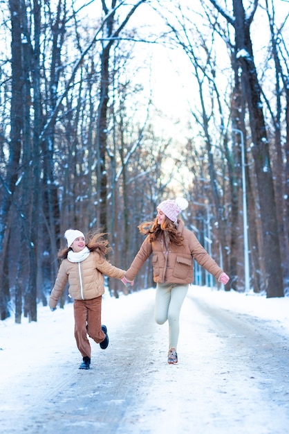 Due ragazze adolescenti divertendosi a giocare con la neve in una giornata invernale innevata nella foresta.