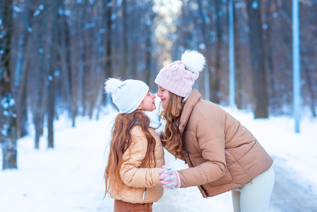 Due ragazze adolescenti divertendosi a giocare con la neve in una giornata invernale innevata nella foresta.