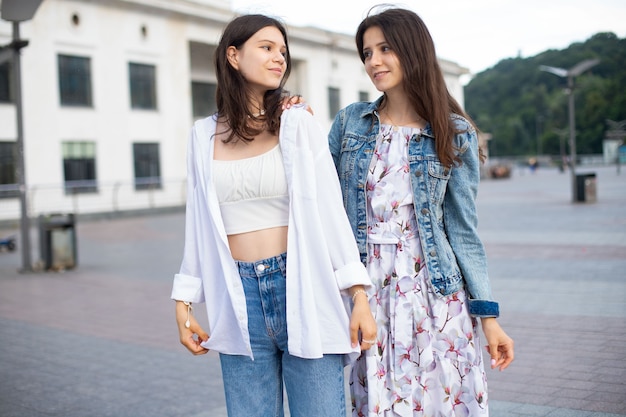 Due ragazze adolescenti in abiti casual che camminano per strada in estate