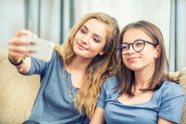 Due ragazze adolescenti sorridono e si fanno un selfie insieme.