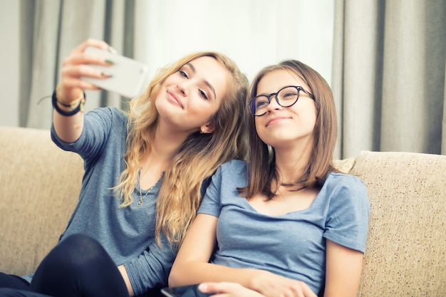 Due ragazze adolescenti sorridono e si fanno un selfie insieme.