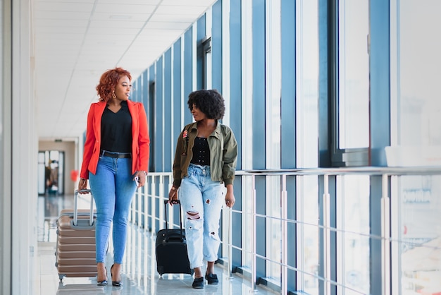 Due ragazze africane con le valigie in aeroporto Il concetto di viaggio e vacanza