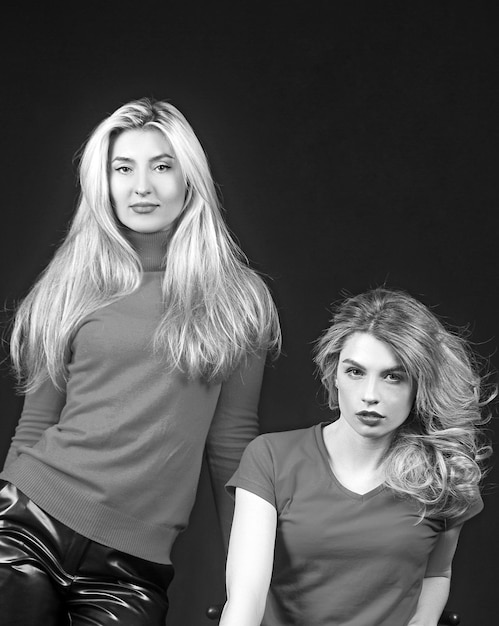 Due ragazze alla moda parlando su sfondo nero Studio shot di graziose signore in rosso