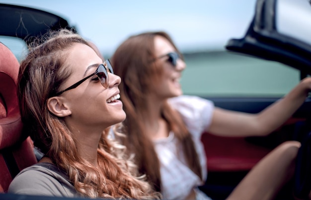 Due ragazze alla moda viaggiano in un'auto decappottabile