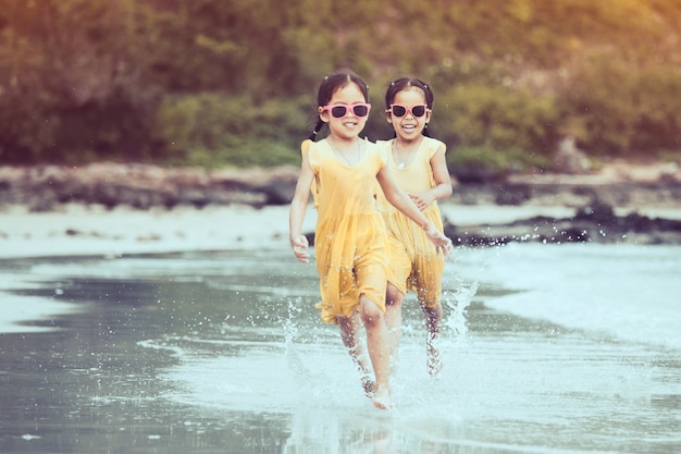 Due ragazze asiatiche del piccolo bambino sveglio che si divertono per giocare ed eseguire