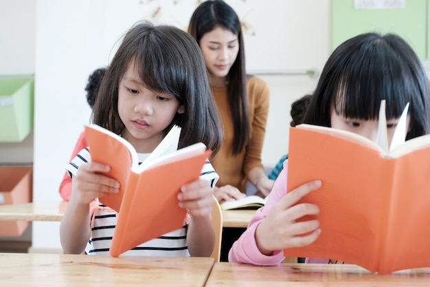 Due ragazze asiatiche, studiando e leggendo un libro nella loro classe, concetto di educazione bambino