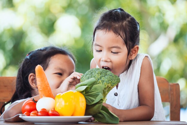 Due ragazze asiatiche sveglie del bambino che si divertono per imparare insieme sulle verdure