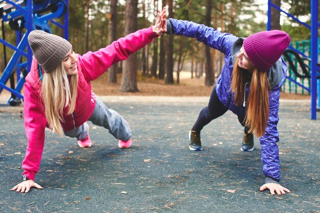 Due ragazze atleti nello sport facendo esercizi fisici nel parco giochi all'aperto nel bosco. Uno stile di vita sano