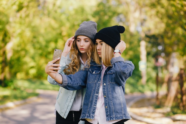 due ragazze belle ed eleganti in piedi in un parco estivo e fare un selfie