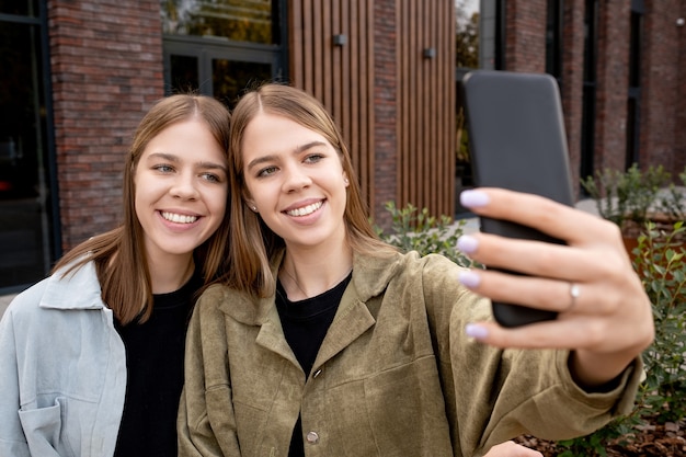 Due ragazze carine con i capelli biondi che fanno selfie all'aperto