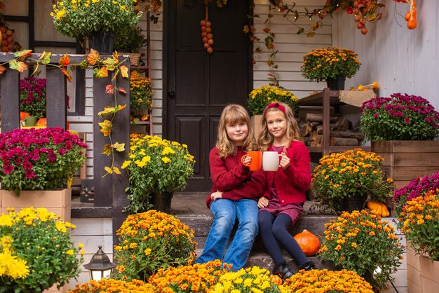 due ragazze carine stanno bevendo il tè per strada in abiti caldi in autunno halloween concept