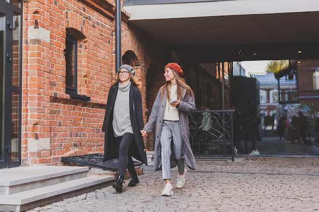 Due ragazze che camminano per strada insieme e si tengono per mano indossano la primavera o l'autunno