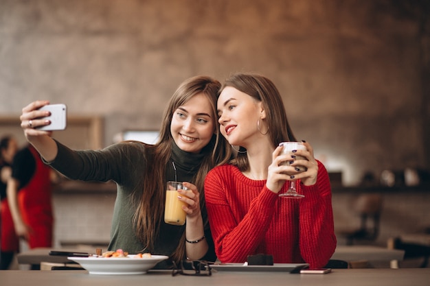 Due ragazze che fanno selfie in un caffè