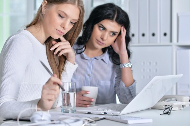 Due ragazze che lavorano in ufficio usando il laptop