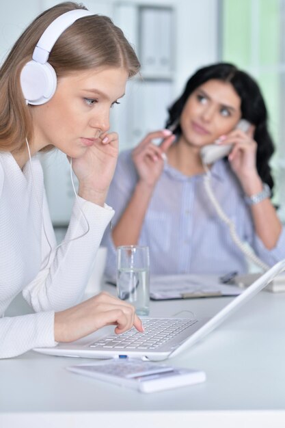 Due ragazze che lavorano in ufficio usando il laptop