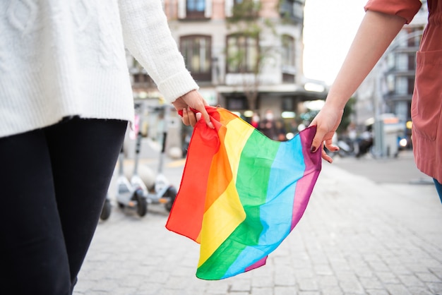 due ragazze che portano la bandiera arcobaleno in giro per la città